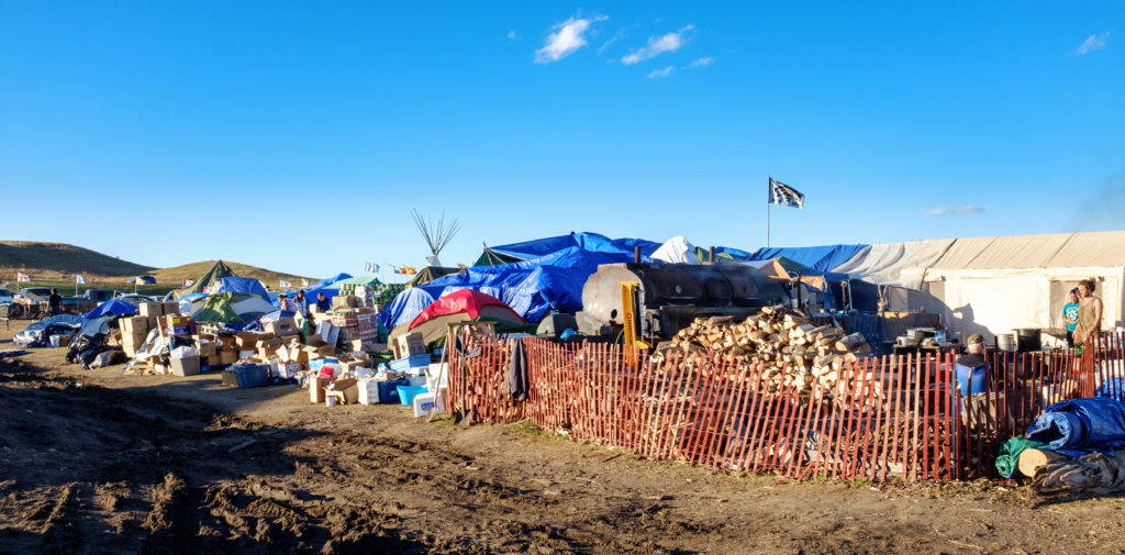 Donations are piled up alongside kitchen and supply tents at the Oceti Sakowin camp. A significant amount of labor at the camps goes into sorting and distributing the supplies that arrive from across the country. Image by author, September 2016.
