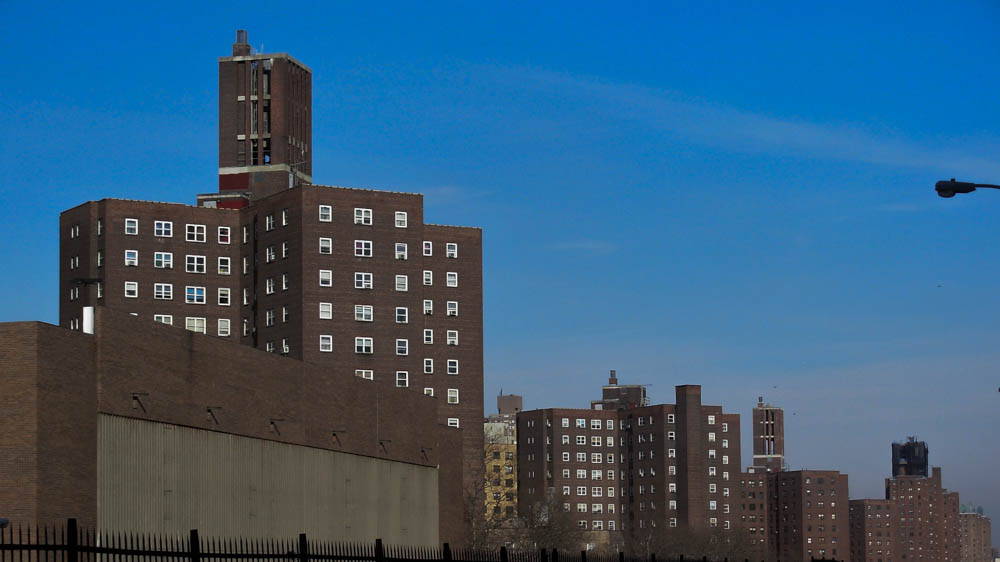 Three brick public housing towers against a blue sky.