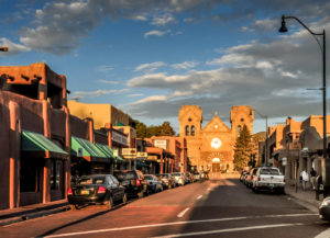 The light of sunset bathes a church at the end of a one-story commercial strip.