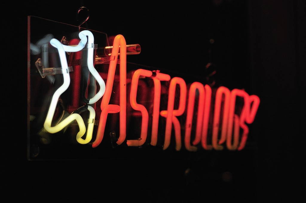 "Astrology" written in neon with a white neon star, on a black background.