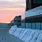 A concrete baffle wall, bags and sand are all that lie between the houses and the rising sea. (November 2014) A concrete baffle wall, bags and sand are all that lie between the houses and the rising sea. (November 2014)