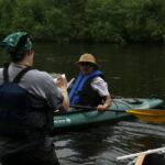 Alison Mikulyuk talks with a kayaker on the Namekagon River about the "Voices of the Namekagon" project. Photo by Jojin Van Winkle, 2016. Alison Mikulyuk talks with a kayaker on the Namekagon River about the "Voices of the Namekagon" project. Photo by Jojin Van Winkle, 2016.