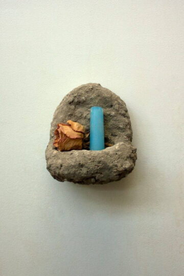 Shrine by J. Leigh Garcia. A small, concrete, wall-mounted shrine with a dried yellow rose and a blue candle stub inside it.