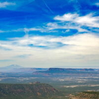 Looking south from the Bears Ears across Cedar Mesa. Navajo Mountain rises in the south. A panoramic photograph of desert mesas and a mountain.