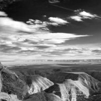 Muley Point. The southern edge of Cedar Mesa. The San Juan River cut the deep canyon seen here. A black and white panoramic photograph of desert canyons.