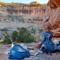 The author's camp on a sandstone bench above the canyon bottom. A photograph of camping gear outside in a desert canyon.
