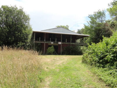 The Pipiriki Hotel today. A two-story building with tall grasses alongside