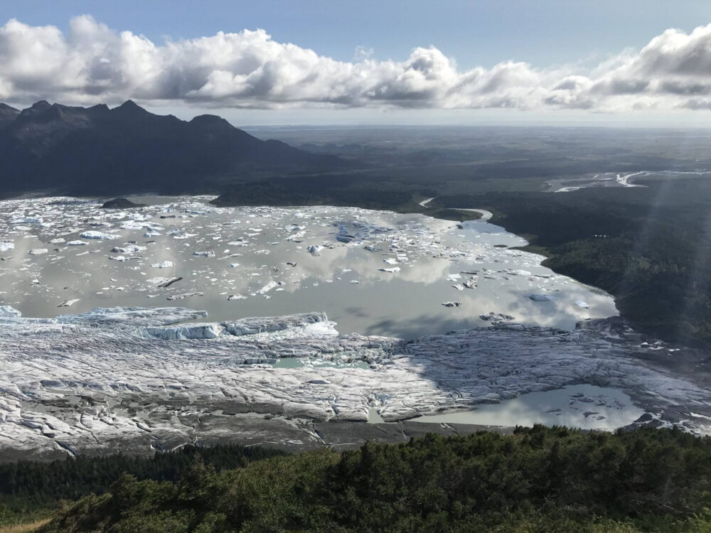 La', Eyak, Alaska. Photo by Jimmy Boy. Frozen glacier beneath mountain and white clouds.