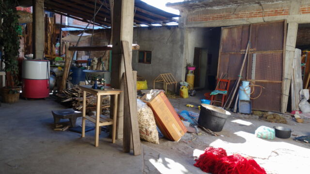 Household workshop, Teotitlán del Valle. In Oaxaca city, courtyards serve as leisure space or places for parking cars. In rural areas, families have room to spread out on surrounding grounds, and tend not to build courtyard homes. But in peri-urban areas, courtyards are often used as workshops for production of goods intended for urban markets. Since the grassland ecology on the mountain slopes around Teotitlán del Valle is good for pasturing sheep, residents produce high quality wool for knitting and weaving in their household workshops. A house's interior open air courtyard typical of Oaxaca's peri-urban landscape, serving as a workshop and storage and filled with supplies like buckets.
