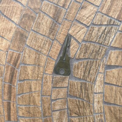 A metal key is embedded in a mosaic sculpture. The mosaics are shades of brown.