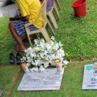 All Souls' Day White flowers on a grave, in front of chairs.